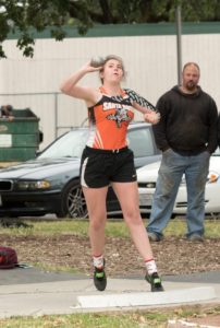 Young woman dancing outdoors while a man watches nearby.