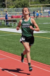 A runner in a green Sonoma Lacrosse uniform on a track.