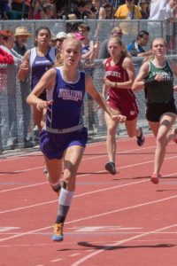 Athlete prepares for pole vault on a track with others watching.
