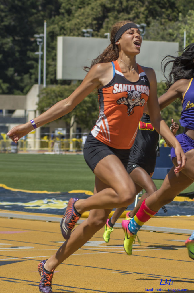 Athlete prepares for pole vault on a track with others watching.