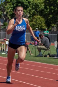 Female athlete sprinting on a track during a race.