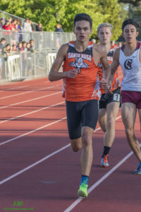 Athlete prepares for pole vault on a track with others watching.