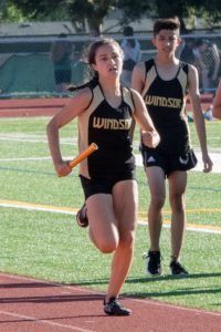 A female athlete sprinting on a track during a race.