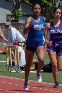 Two female runners competing on a track during a race.