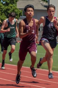 Three athletes sprinting on a track during a race.