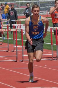 Athlete competing in a hurdles race on a track.
