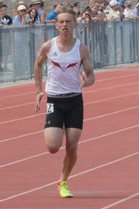 Athlete sprinting on a red track during a race.