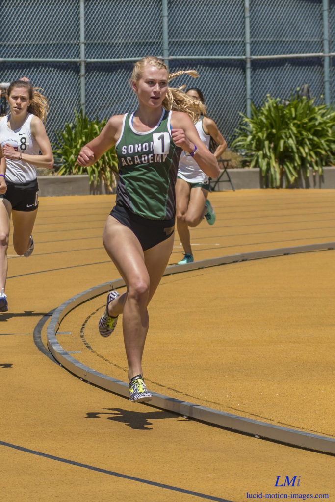 Athlete prepares for pole vault on a track with others watching.