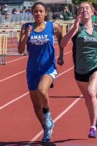 Two runners competing on a red track during a race.