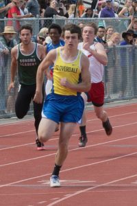Athlete prepares for pole vault on a track with others watching.