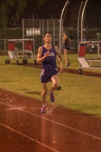 Athlete prepares for pole vault on a track with others watching.