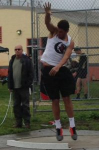 A young man in sportswear performs a basketball move outdoors.