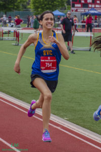 Athlete prepares for pole vault on a track with others watching.