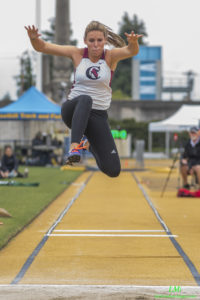 Athlete prepares for pole vault on a track with others watching.
