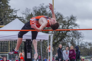 Athlete performing a high jump over the bar at an outdoor event.