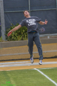 Athlete prepares for pole vault on a track with others watching.