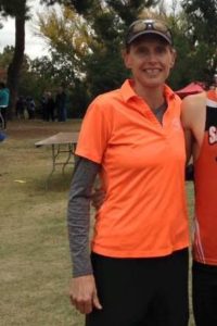 Person in bright orange shirt smiling outdoors at event.