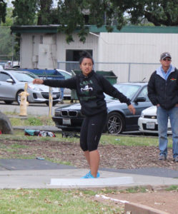 Woman preparing to throw a shot put during an outdoor event.