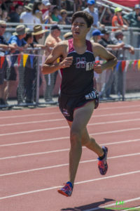 Athlete prepares for pole vault on a track with others watching.
