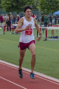 Athlete prepares for pole vault on a track with others watching.