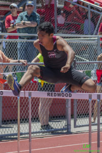 Athlete prepares for pole vault on a track with others watching.