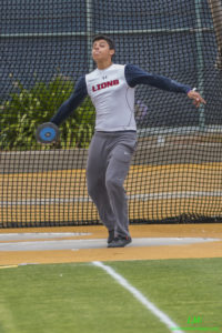 Athlete prepares for pole vault on a track with others watching.