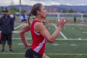 Athlete prepares for pole vault on a track with others watching.