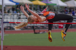 Athlete mid-air clearing the high jump bar during a track event.