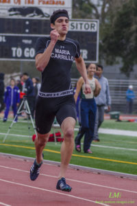 Athlete prepares for pole vault on a track with others watching.