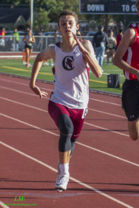 Athlete prepares for pole vault on a track with others watching.