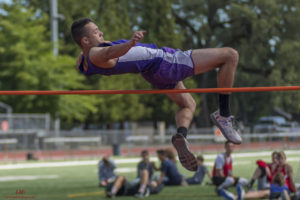 Athlete executing a high jump over the bar outdoors.