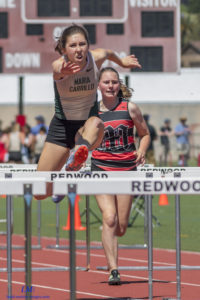 Athlete prepares for pole vault on a track with others watching.