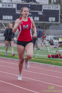 Athlete prepares for pole vault on a track with others watching.