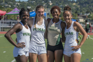 Four female athletes in Puma and Oak-Charlotte sportswear posing outdoors.