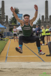 Athlete prepares for pole vault on a track with others watching.