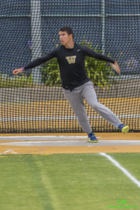Athlete prepares for pole vault on a track with others watching.