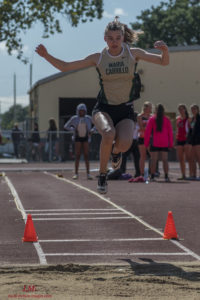 Athlete mid-air during a long jump at a track event.