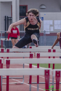 Athlete mid-air hurdling during a race.
