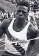 Athlete prepares for pole vault on a track with others watching.