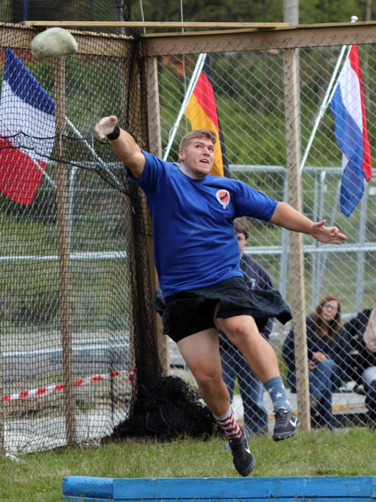 Athlete prepares for pole vault on a track with others watching.
