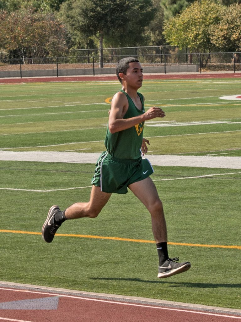 Athlete prepares for pole vault on a track with others watching.