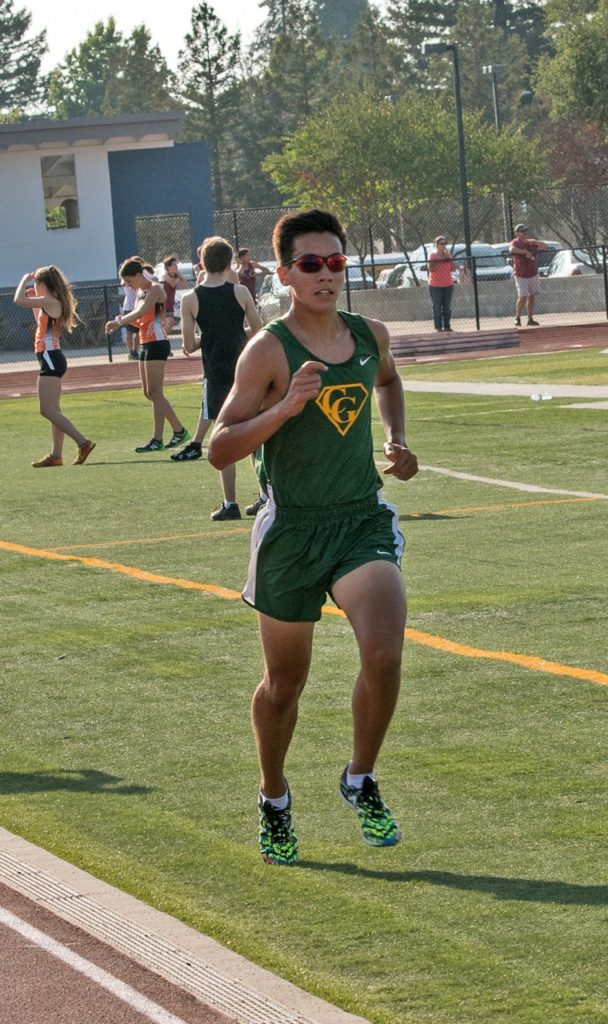 Athlete prepares for pole vault on a track with others watching.