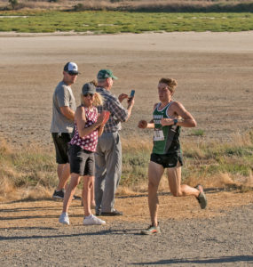 Athlete prepares for pole vault on a track with others watching.