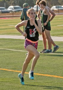 Athlete prepares for pole vault on a track with others watching.