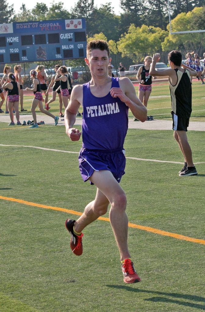 Athlete prepares for pole vault on a track with others watching.