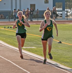 Athlete prepares for pole vault on a track with others watching.