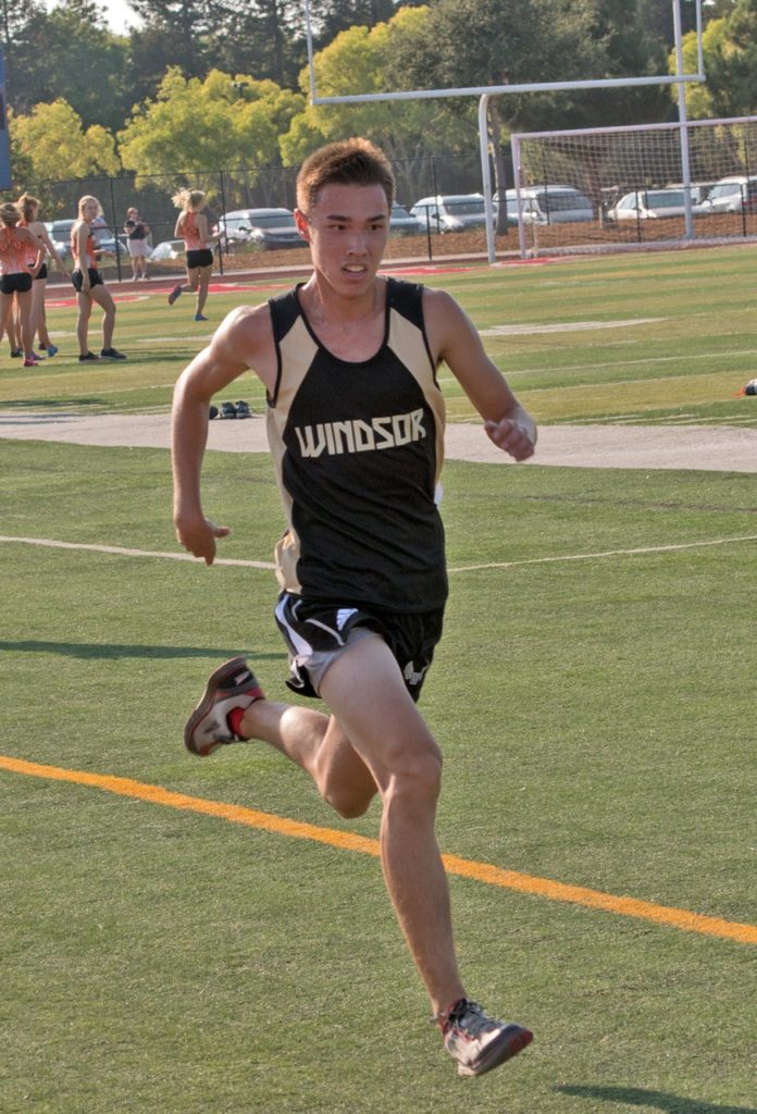 Athlete prepares for pole vault on a track with others watching.