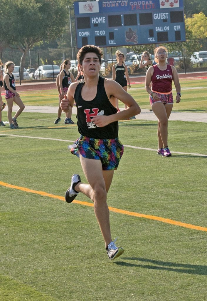 Athlete prepares for pole vault on a track with others watching.