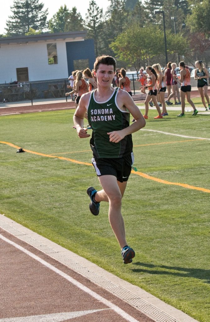 Athlete prepares for pole vault on a track with others watching.