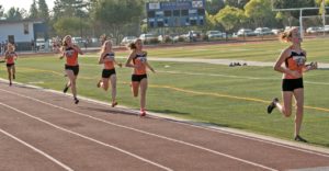 Athlete prepares for pole vault on a track with others watching.